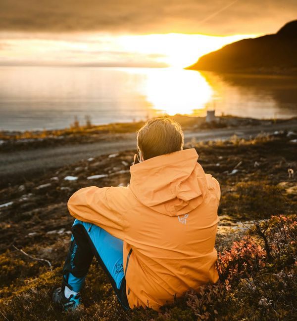 Person meditating in a serene natural environment at sunrise.